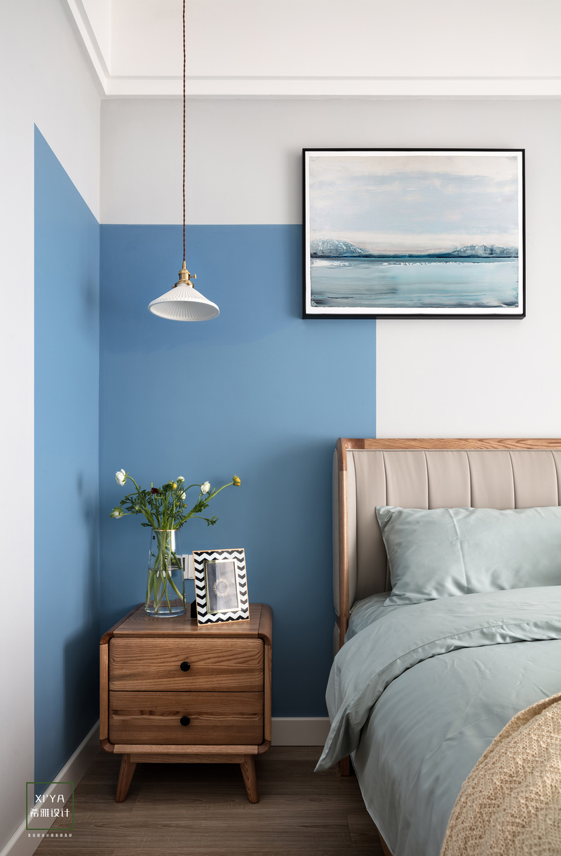主卧室背景部分，采用色块的设计，蓝色与浅灰色中间，用一幅蓝色系的挂画，两者起到衔接，延伸的效果。蓝色代表宁静，搭配造型简约的吊灯加以点缀，柔和的灯光，照亮整个主卧室，让人身心放松。