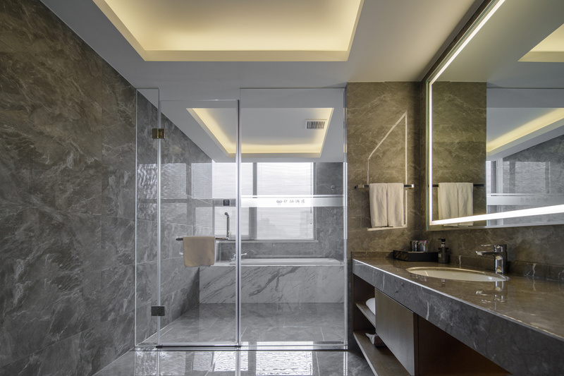 客房的浴室整体采用大理石材质，以灰色为主色调，简洁而质朴，颇有侘寂之风。设计师按照生活场景和需求，采用玻璃门做了干湿区分离的设计，让光线渗透到方寸之间，悄然提升着生活的质感。