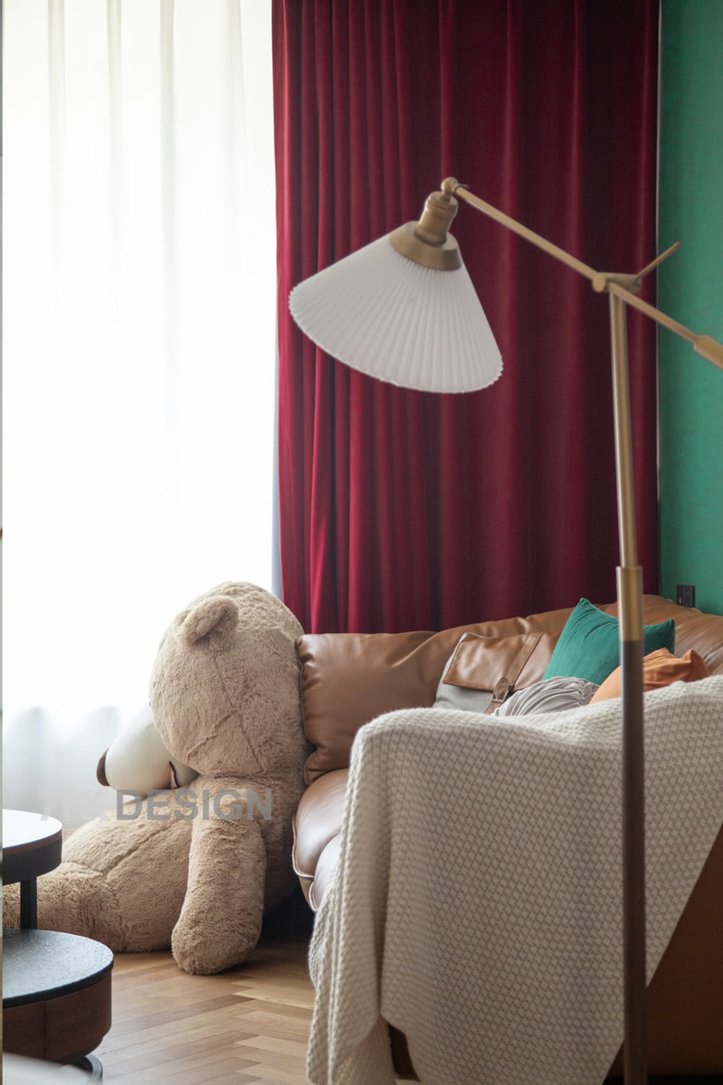 沙发一角用黄铜色落地灯增加空间氛围感，抢镜的玩具熊仔慵懒的躺在地面上，使得空间多了几分趣味。
