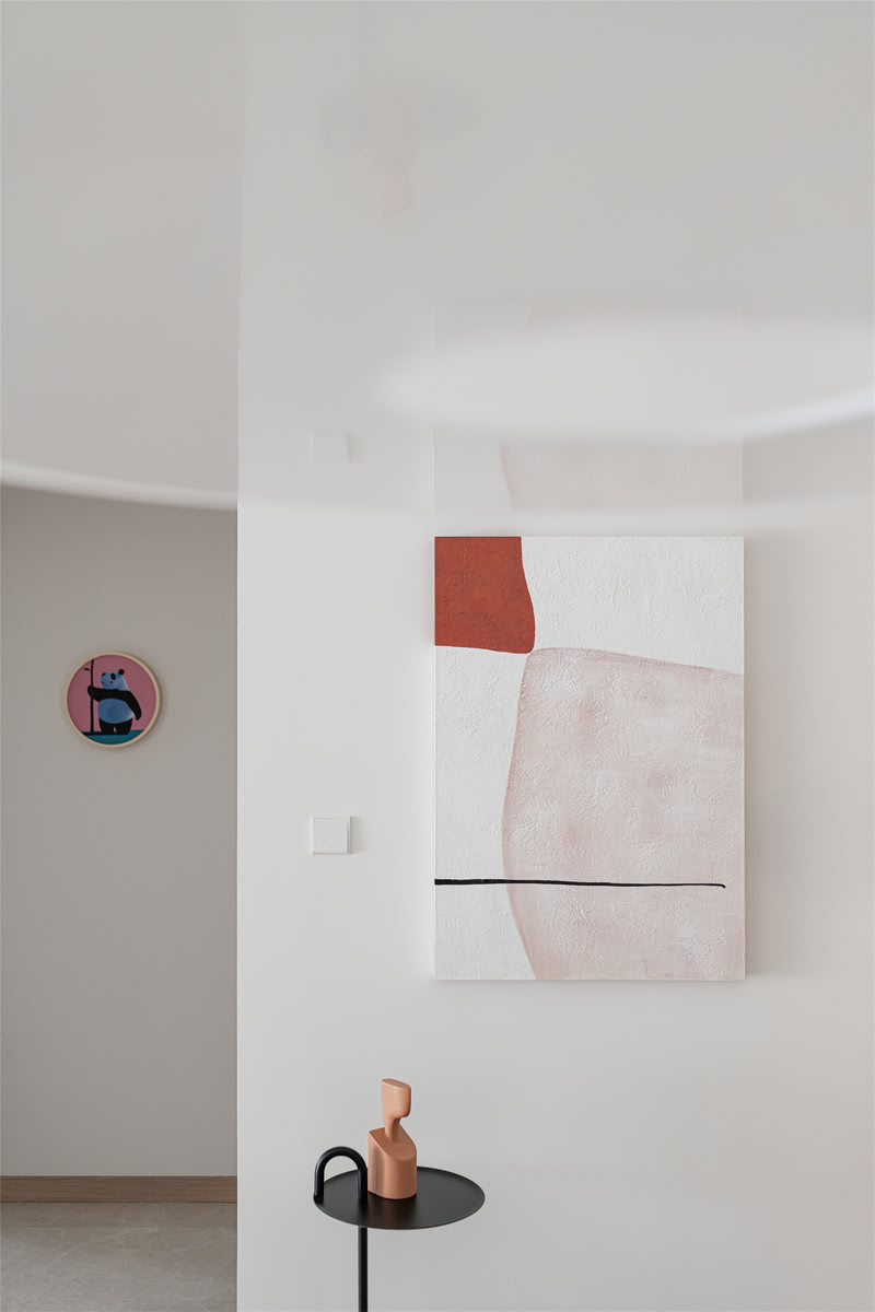 玄关处的抽象挂画搭配造型简单的HAY边桌，散发出简约派专属的艺术气息，引导着居住者进入清新自然的室内空间。