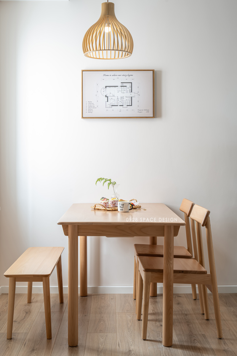 木质餐桌椅，顶上一盏藤编吊灯，搭配木质边框的户型平面布置图挂画，是设计师送给业主的新居之礼，一副由家里的平面图打印的挂画，非常有意义。