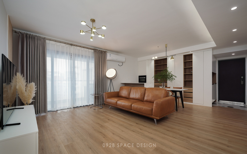 皮质沙发与木地板的搭配，温馨舒适，阳台通过纱窗透进来的光，给整个空间营造了一种安逸之感。