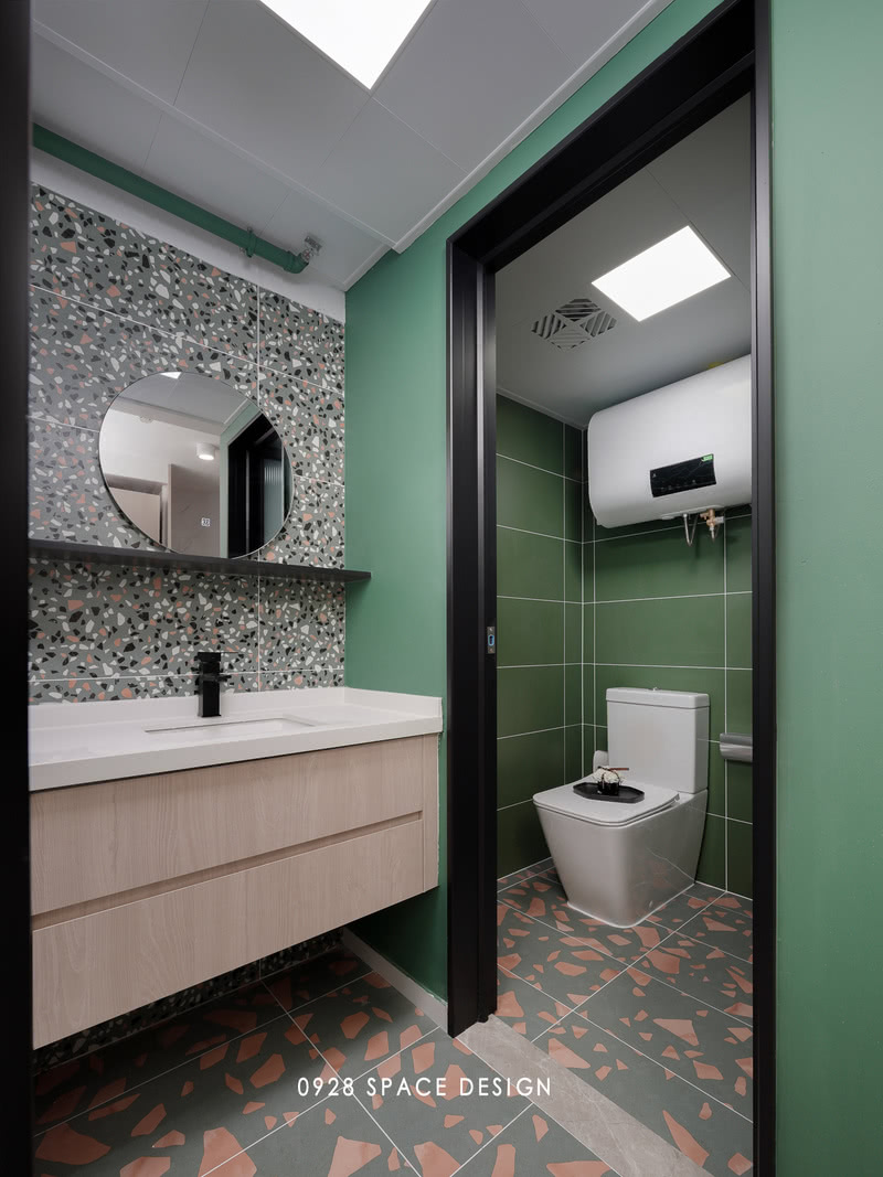 卫生间背景墙以墨绿色为主，地板则用水磨石花色瓷砖，马桶区与淋浴区分开，更方便日常的使用。