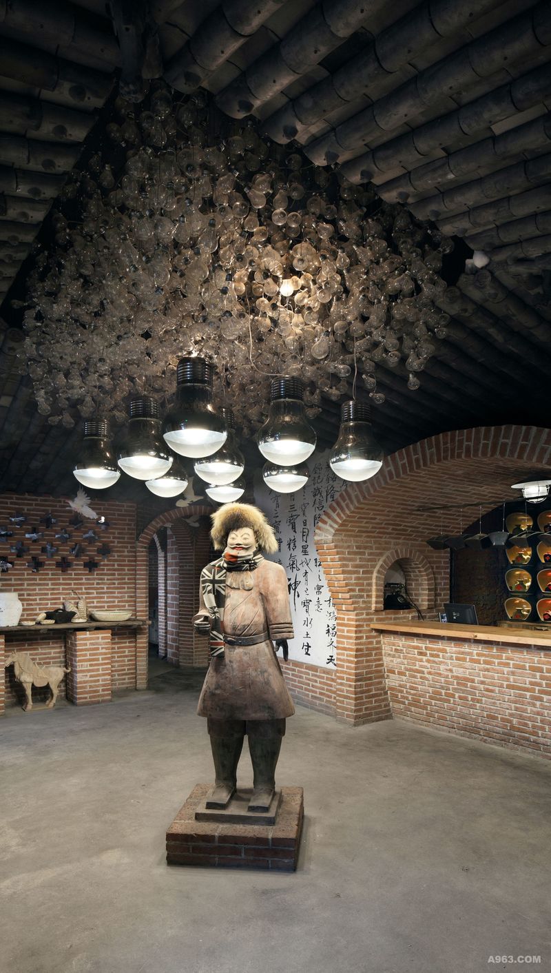 步入前厅迎面是微笑的陶俑，灰瓦和灯泡组合构成的倒挂四水归堂的天井更是给宾客带来空间翻转的新视觉。