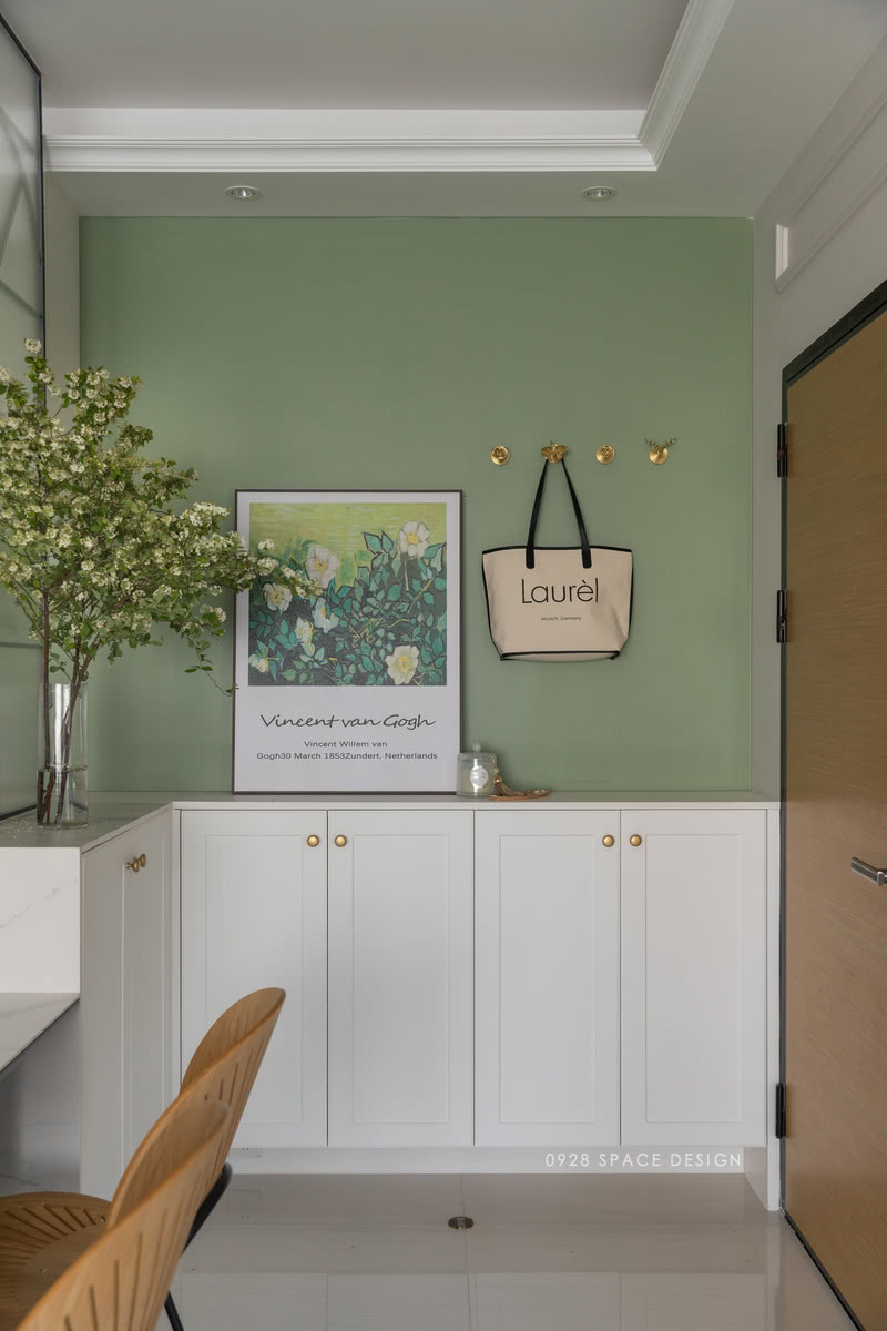 绿色的墙面和白色的储物柜，配色清新自然，玄关做半高的L型鞋柜，底下镂空方便摆放家居鞋。