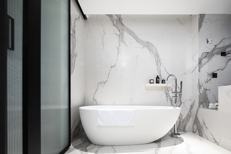 白色落地式独立浴缸搭配银色洁具，纯净中透露着高级感。墙面加设岩板置物架，洗浴用品可以随手搁置，便捷又实用。