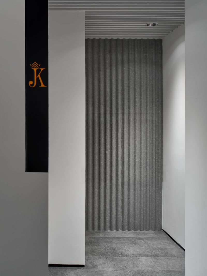 卫生间入口设计
灰色乳胶漆墙面嵌入黑色金属镂空设计，融入橙色元素点缀的卫生间标识及入口处灰色弧形石材在柔和的灯光下使空间更具丰富的层次感，体现公司对细节设计的高要求。
