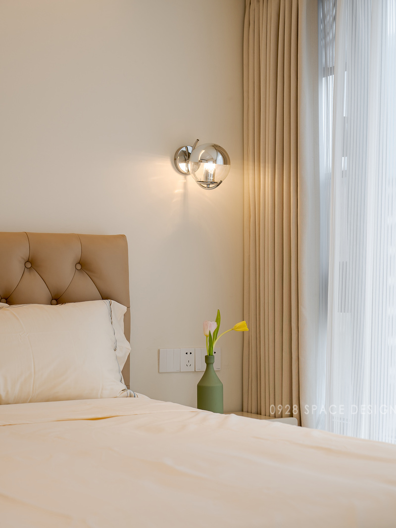 床头两边以款式不一的壁灯装饰，银色与玻璃的搭配让高级感倍增，拼色床头柜给纯色的背景墙增添了几分色彩。