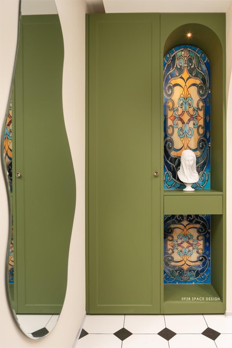 橄榄绿的柜子，弧形凹槽抽屉做端景，彩绘玻璃背景，上方一盏小的筒灯照射在石膏像上，显得文艺而端庄。