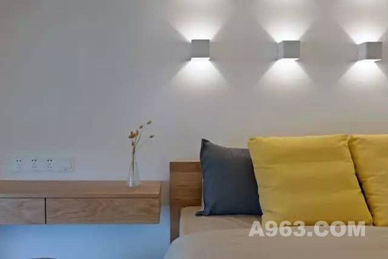 床头背景用壁灯来装饰，为卧室提供柔和的灯光。
