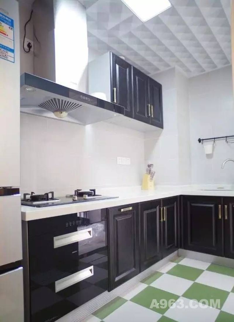 ▲黑色的厨柜与白色墙砖是最经典的搭配，地面则延续了轻快的风格，绿色和白色相间的地砖透着淡淡的自然气息。