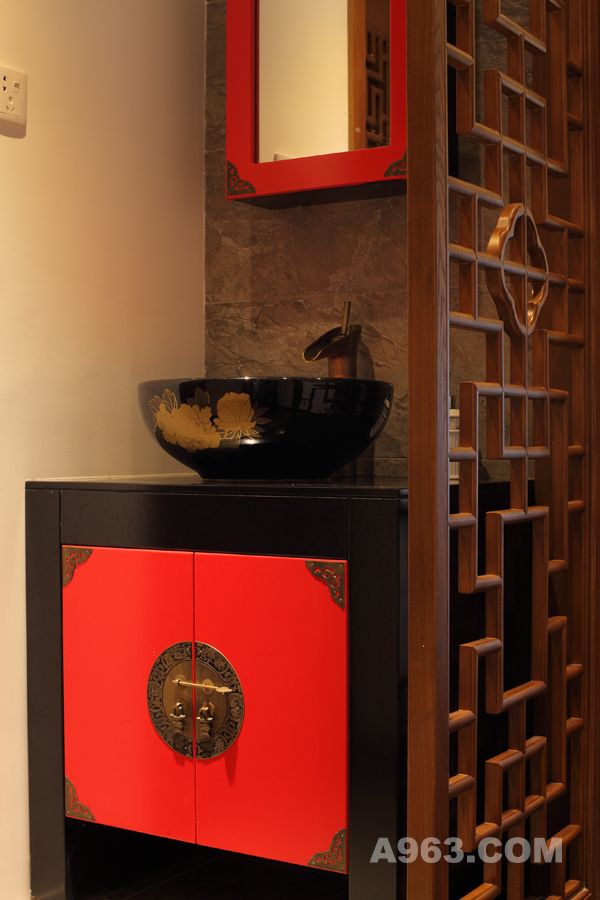 红色柜身，红黑相间的洗手盆，传统的中式纹样镂空隔断，与门上的木纹样雕花相呼应，这些元素的运用，在古木色的空间里更显张力。柜面上的雕花花纹、古风拉手，细节处处体现中式元素的优雅，使得此处成为整套房屋的一个装饰亮点所在。