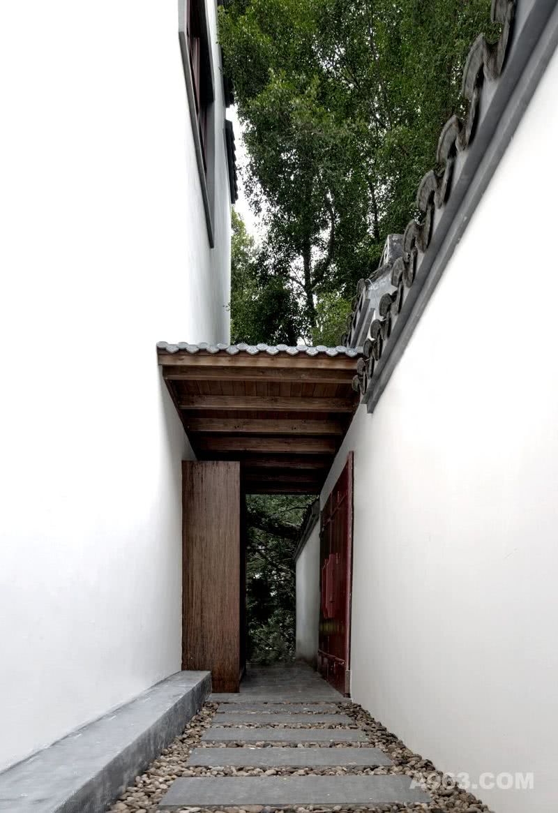 白色高墙与木板石子构成通向入口的走廊