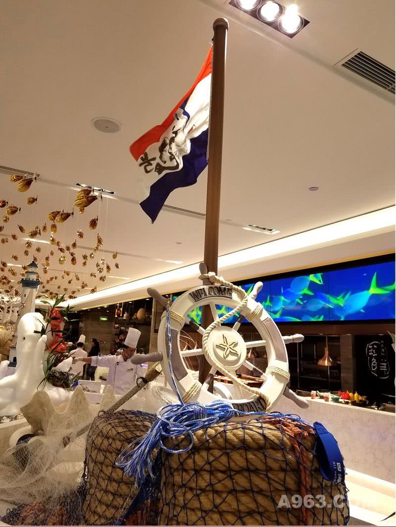 这面带有企业LOGO旗帜，设立在初色餐厅的大自助餐区的一艘大冰船的上方，为了视觉效果更好，在旗杆端头设了出风口，这样就可以让旗帜一直飘扬起来，带有节奏和动感，让餐厅更显热情。