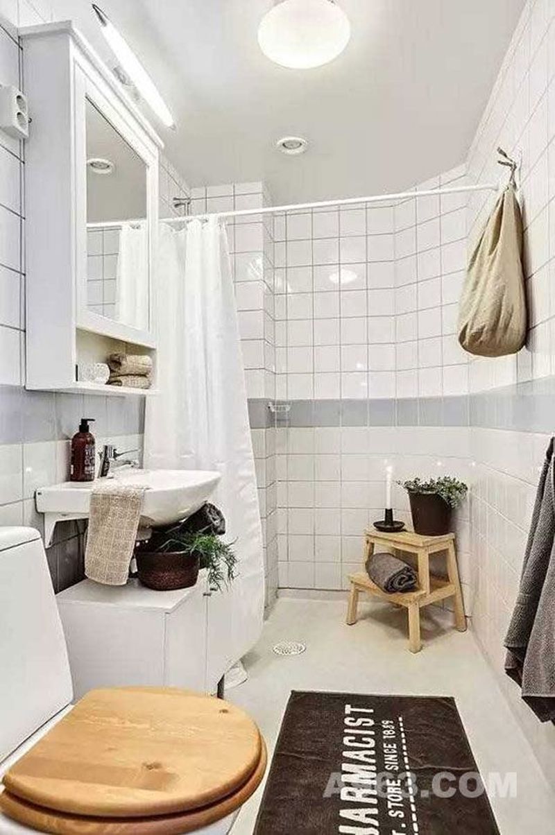 玄关右手边的浴室也是以白色为主。白色的瓷砖和白色柜橱搭配白色的灯光，浴室看起来明亮且不拥挤。放上几盆绿植，净化空气。