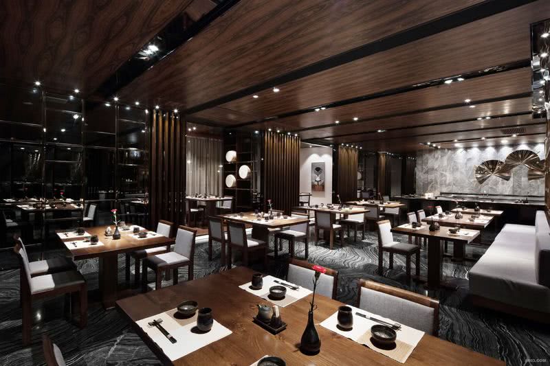 开放餐区A区3-选用相对较暗的黑色，酸枝木色为空间主调，局部搭配亮眼的金色不锈钢扇形挂饰，打破暗调空间的沉闷。
