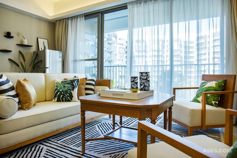 这套户型呈现一种纯朴且毫无矫饰的东南亚风格。客厅抱枕与地毯的选择上汲取了黎族服饰文化，以黑棕色为基本色调，青、红、黄、白相间。饰品使用原木、玻璃、藤编的材质加以绿色植物做为点缀，搭配深色木质家具展现出海南民俗的度假风情。