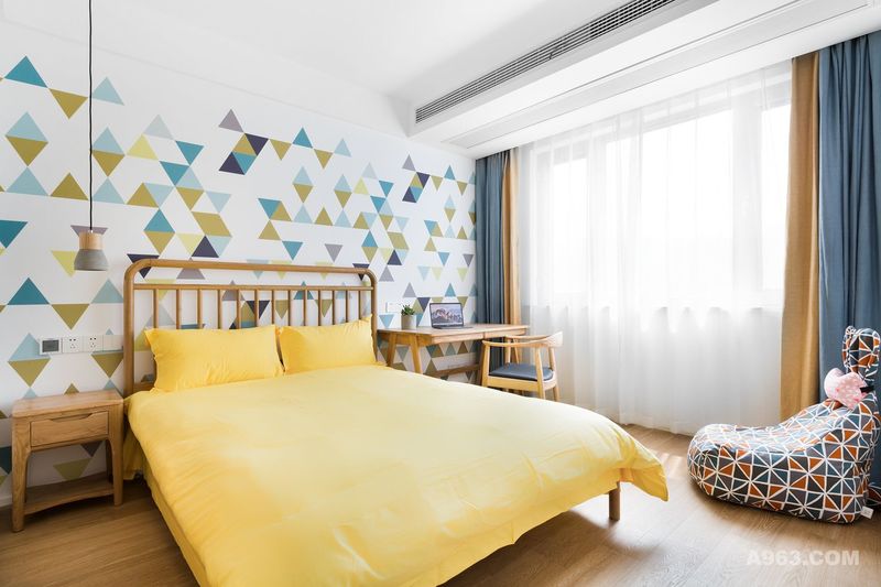 次卧的功能对应的是儿童房，色彩活泼，几何造型的墙纸、撞色窗帘、亮黄色的床品，温馨感十足。