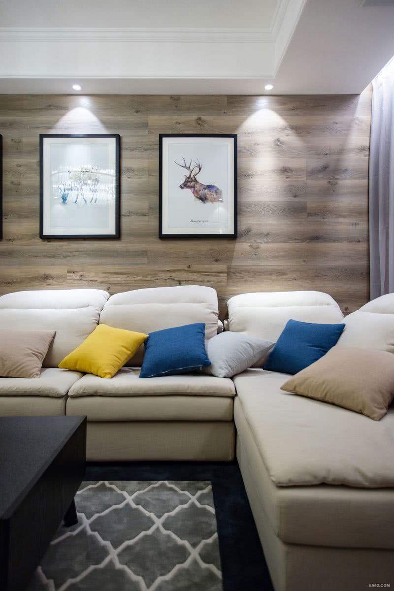客厅一角，宽大的布艺沙发，几乎是居家沙发中最舒适最实用的选择，墙壁上的麋鹿乃吉祥祥瑞的动物，提升整个空间祥和的氛围。