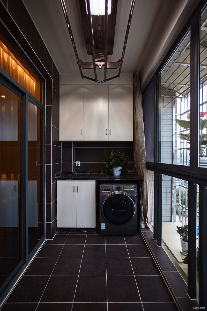 阳台洗衣机台面及储物柜很好的利用了洗衣机上方、侧面的空间，全黑色地砖饰面，和全房设计风格保持一致。