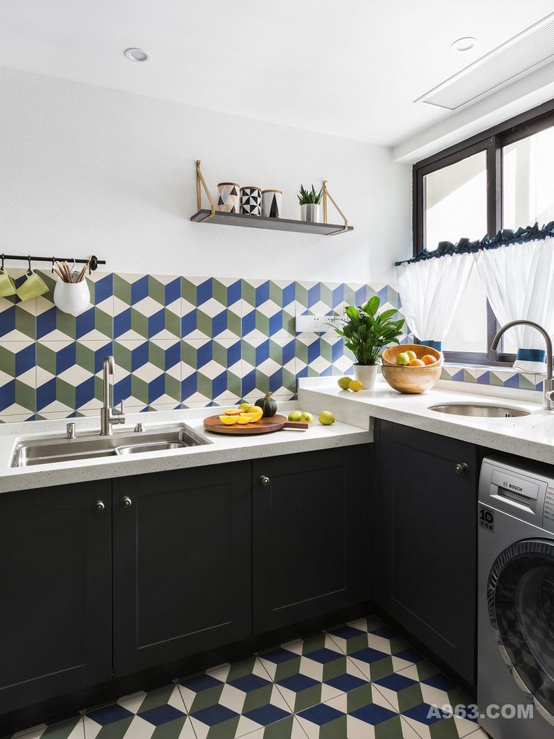 厨房通过空间改造后变的很大，加上女主人并不是很经常在家做饭，所以把洗衣的功能也并入厨房空间。蓝绿相间的几何花砖搭配黑色的橱柜，让传统的厨房变的新颖又有特色。
