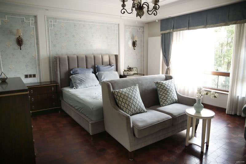 浅蓝色的墙纸将灰色的床衬托的优雅唯美，内设沙发方便主人看电视，卧室清爽舒适。