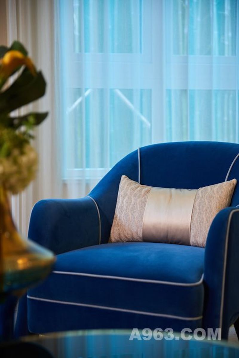 在浅色系家具中以深色绒面单椅提升空间层次，辅以适度饰品摆设，让整个客厅更加丰富饱满。