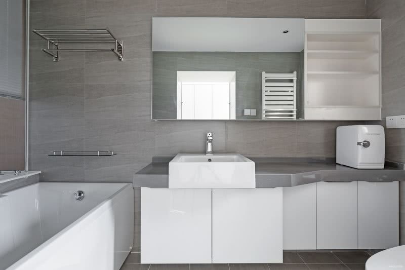 仿石材墙砖、白色调的浴室柜、灰色的洗手台及大面积镜柜使空间整洁宽敞。