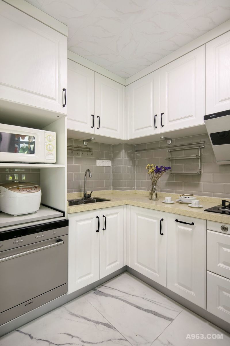 厨房采用米白色调，进门左侧设计高柜，摆放消毒碗柜、微波炉和烤箱